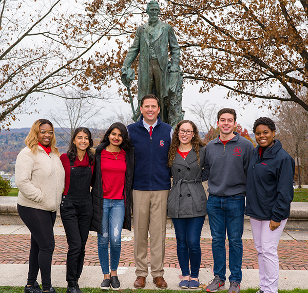 Ryan Lombardi posing with six students in front of Ezra Cornell statue