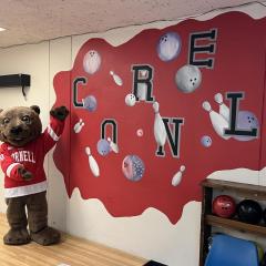 Touchdown the Bear next to mural in bowling alley