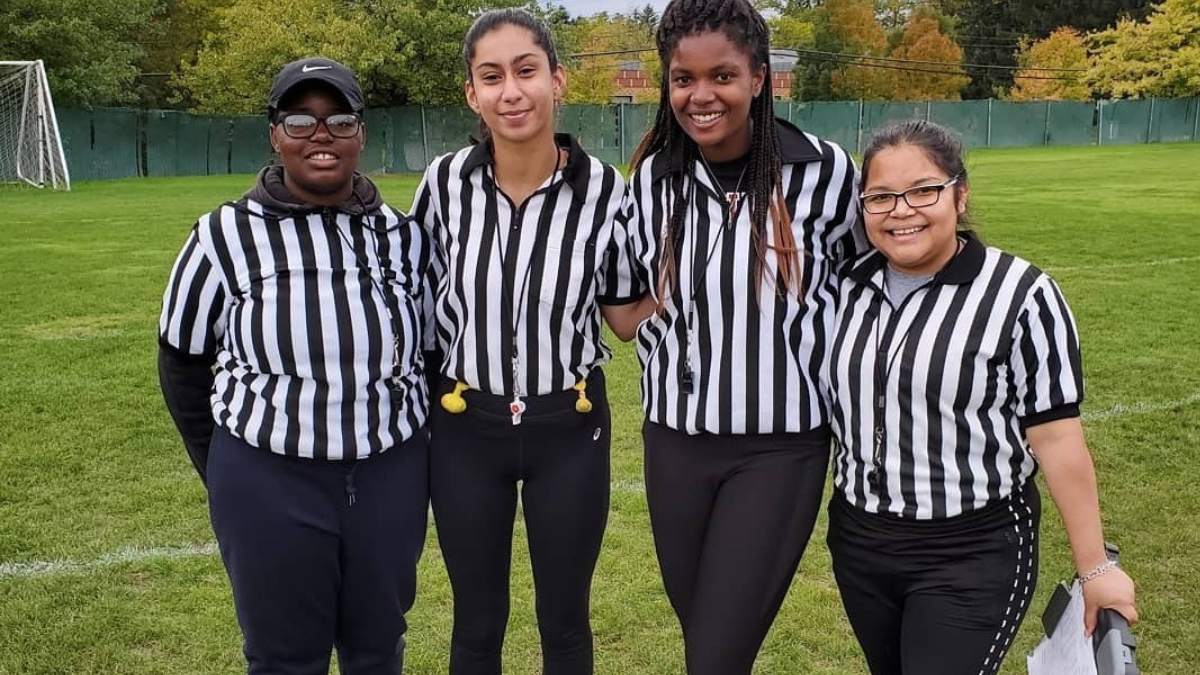 Four referees standing on a playing field