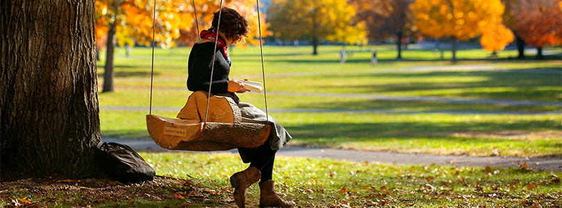 Student sitting on a swing studying