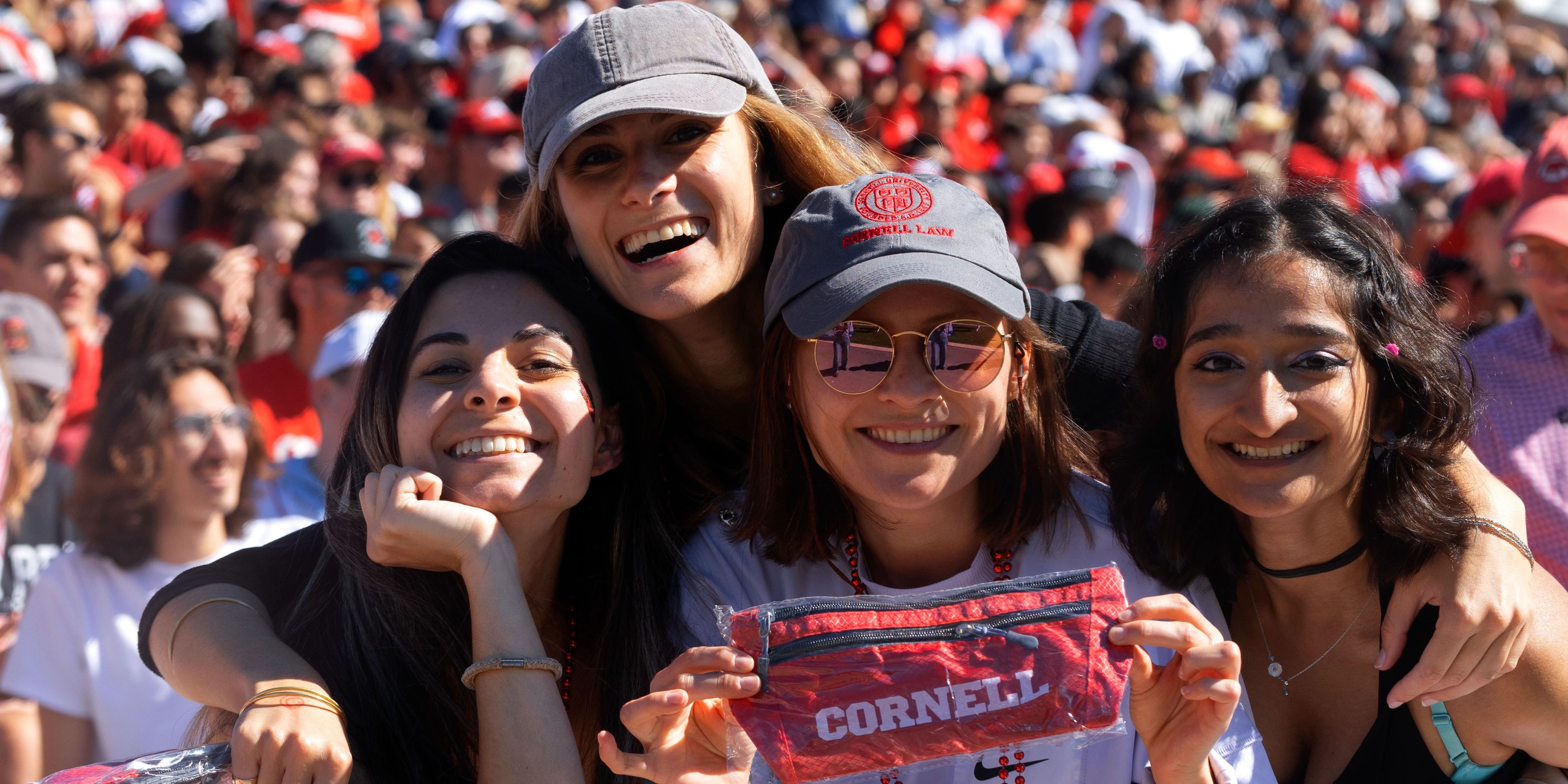 Four students pose for photo while cheering on Cornell at Homecoming 2022.