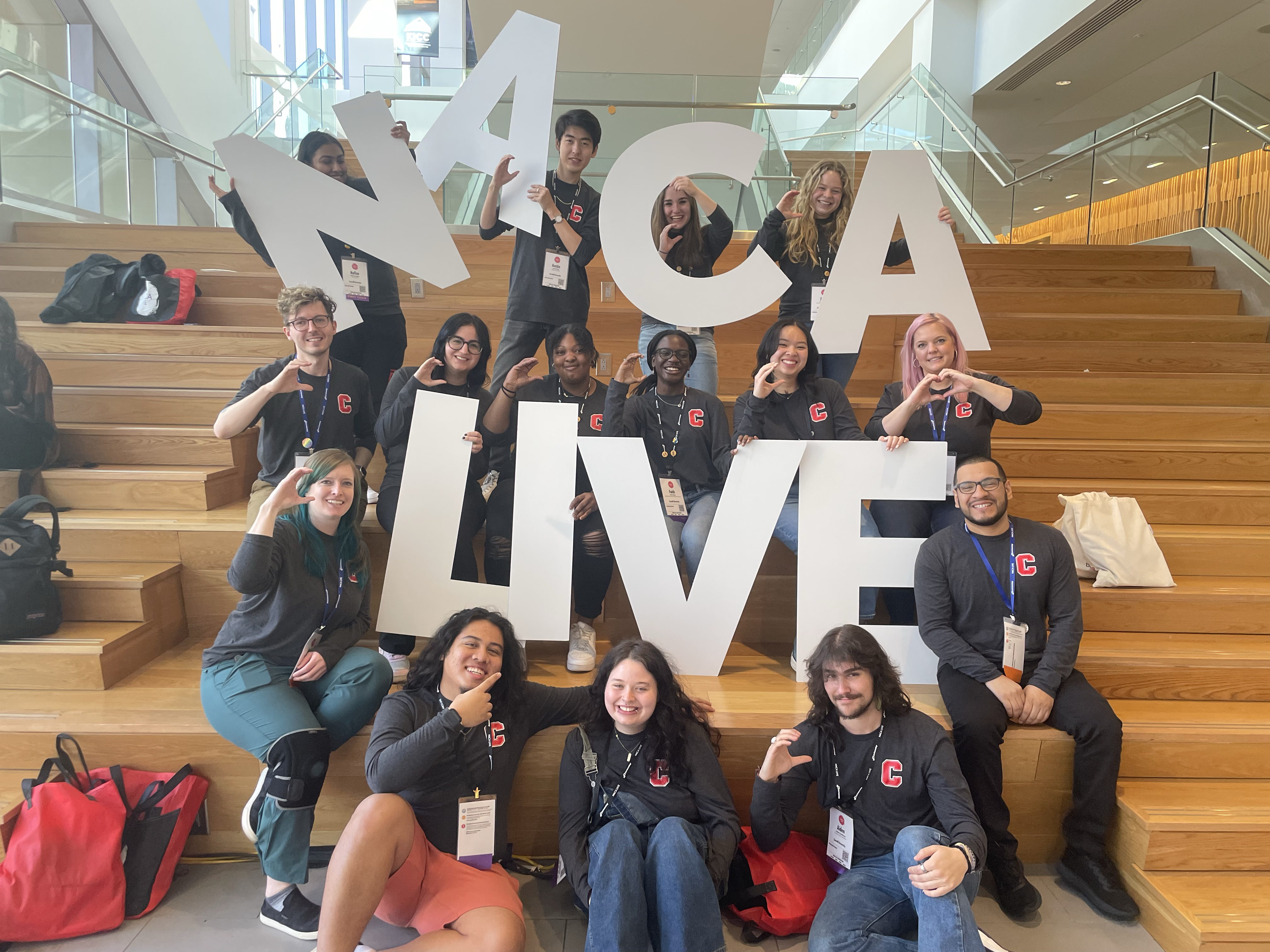 Group of Cornell students and staff holding giant letters spelling "NACA Live"