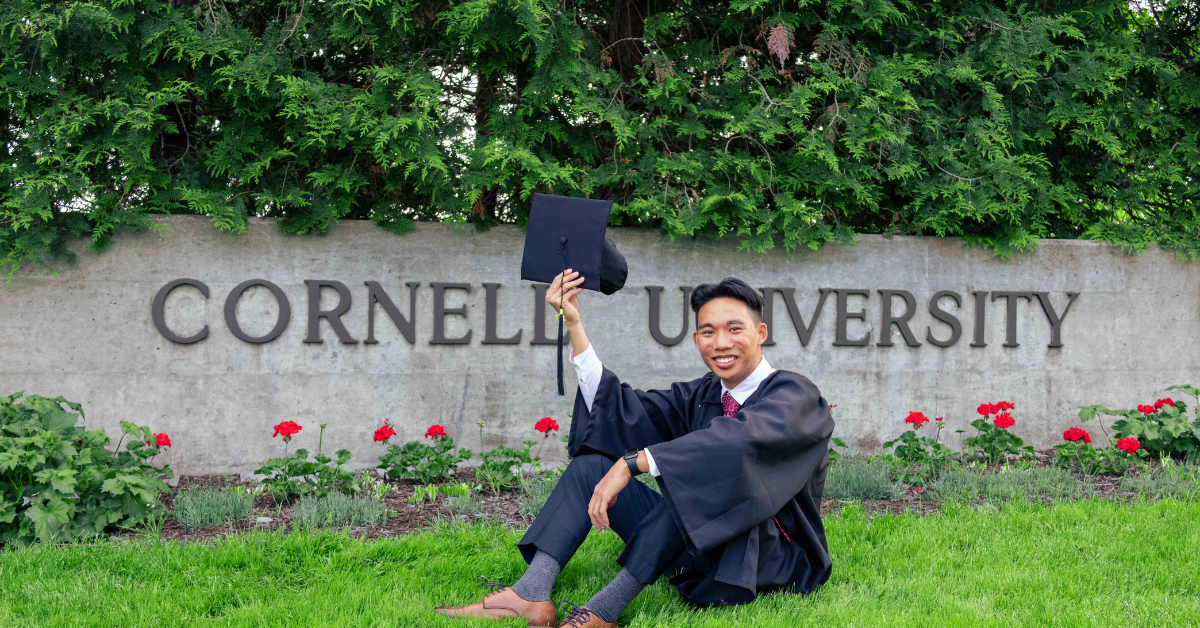 Justin as grad in front of Cornell University sign