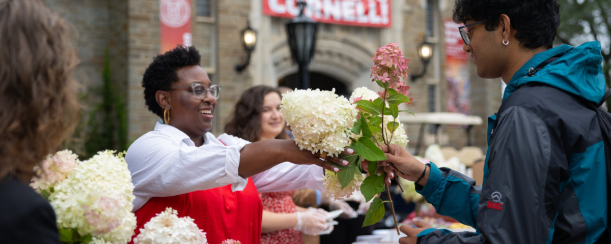Marla Love hands out hydrangeas near Willard Straight Hall during the first day of classes for Fall semester.