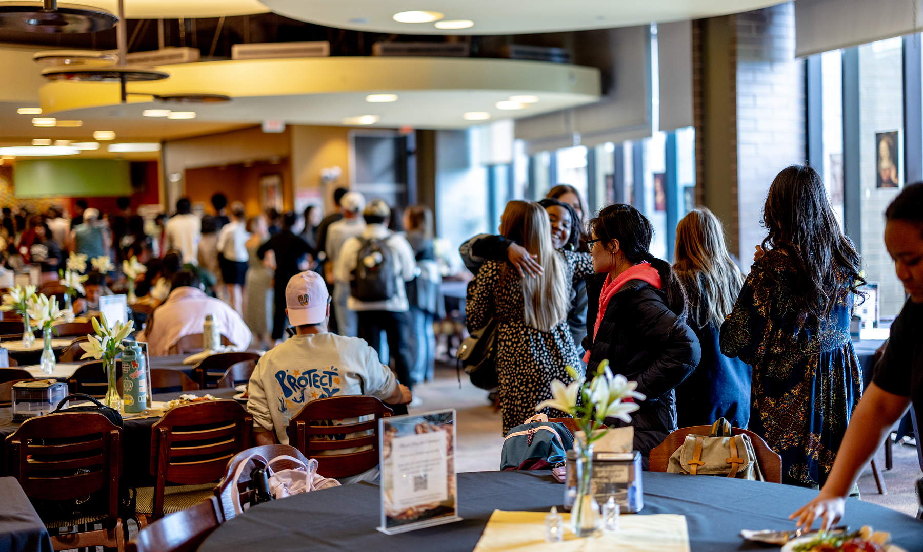 People seated at dining room tables and in line for food