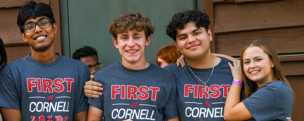 Four students pose wearing shirts that say "First at Cornell."