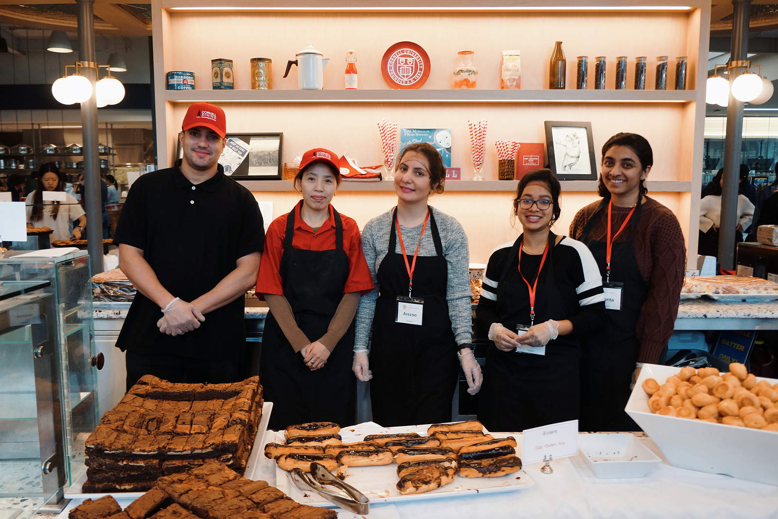 Five people in aprons line up behind a counter