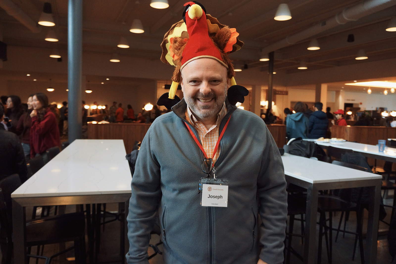 A smiling person wears a felt hat that looks like a turkey