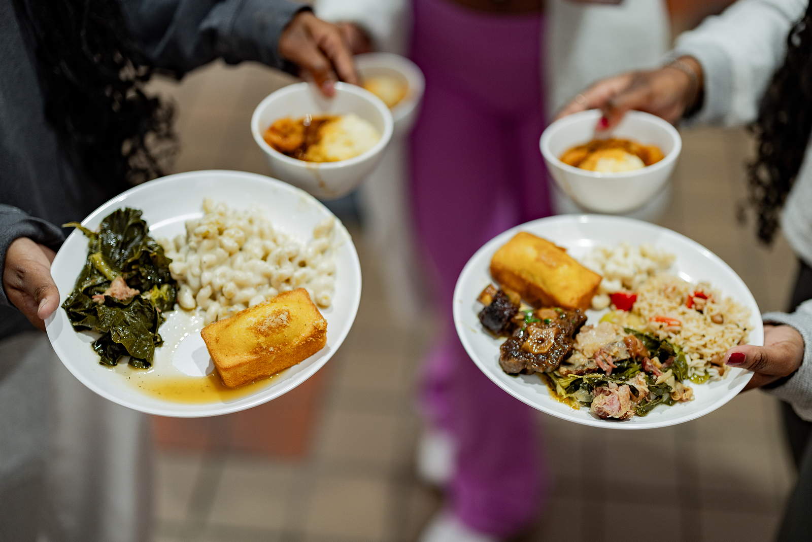 Hands hold plates of food