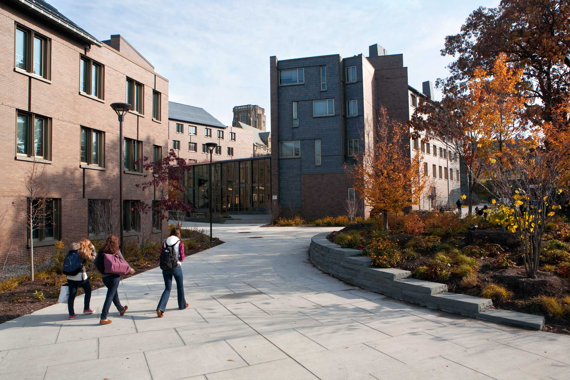 three students carrying bags walking across west campus