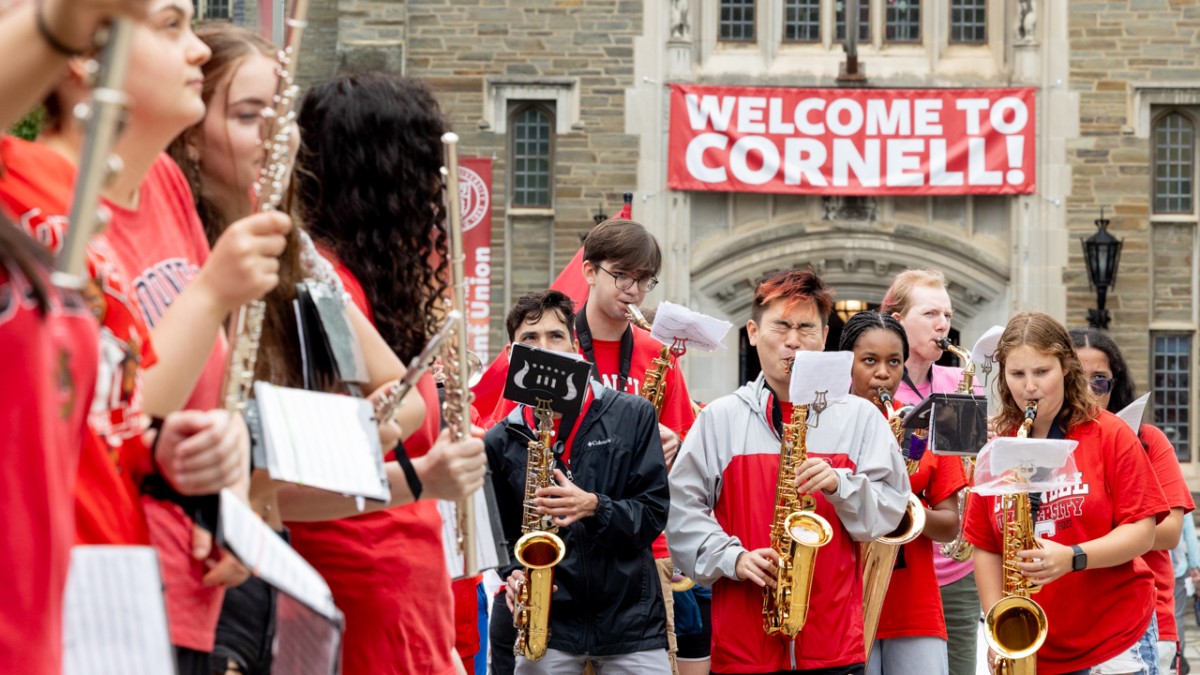 Cornell band playing in front of a Welcome to Cornell banner