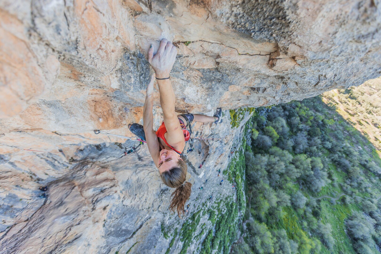 woman climbing up rock with hand covered in chalk dusk