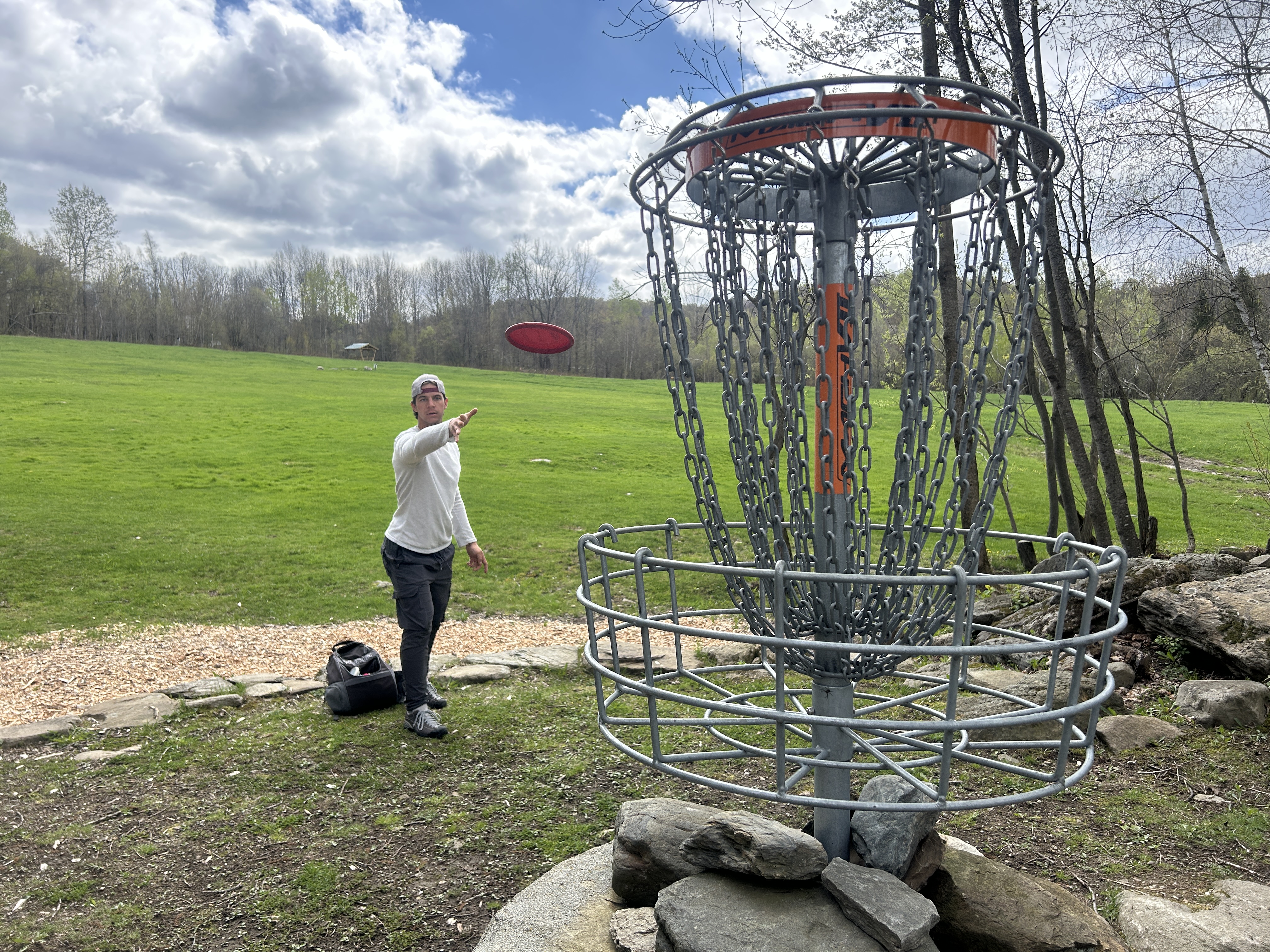 A disc golfer putts toward a basket