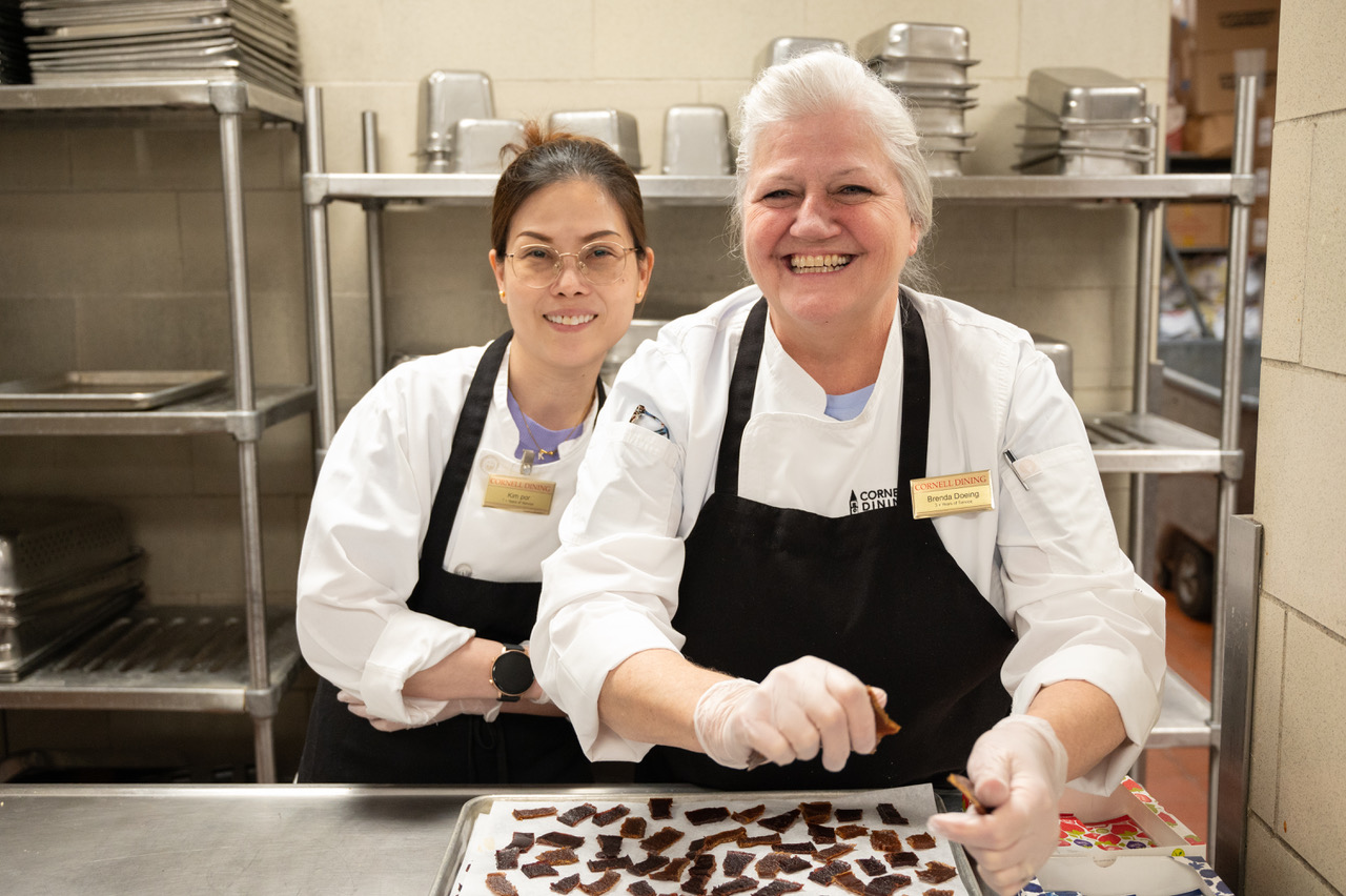 Two smiling cooks in chef coats and aprons