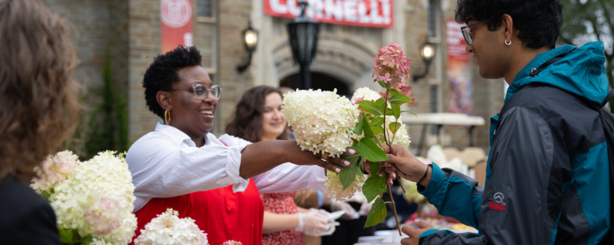 Marla Love hands out flowers in front of Willard Straight Hall