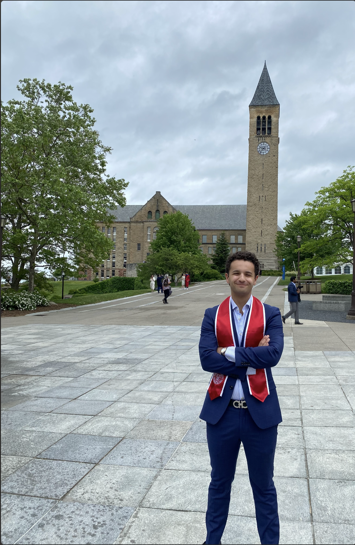 Andrew Lorenzen '22 stands in front of the clock tower on Cornell's campus after graduating