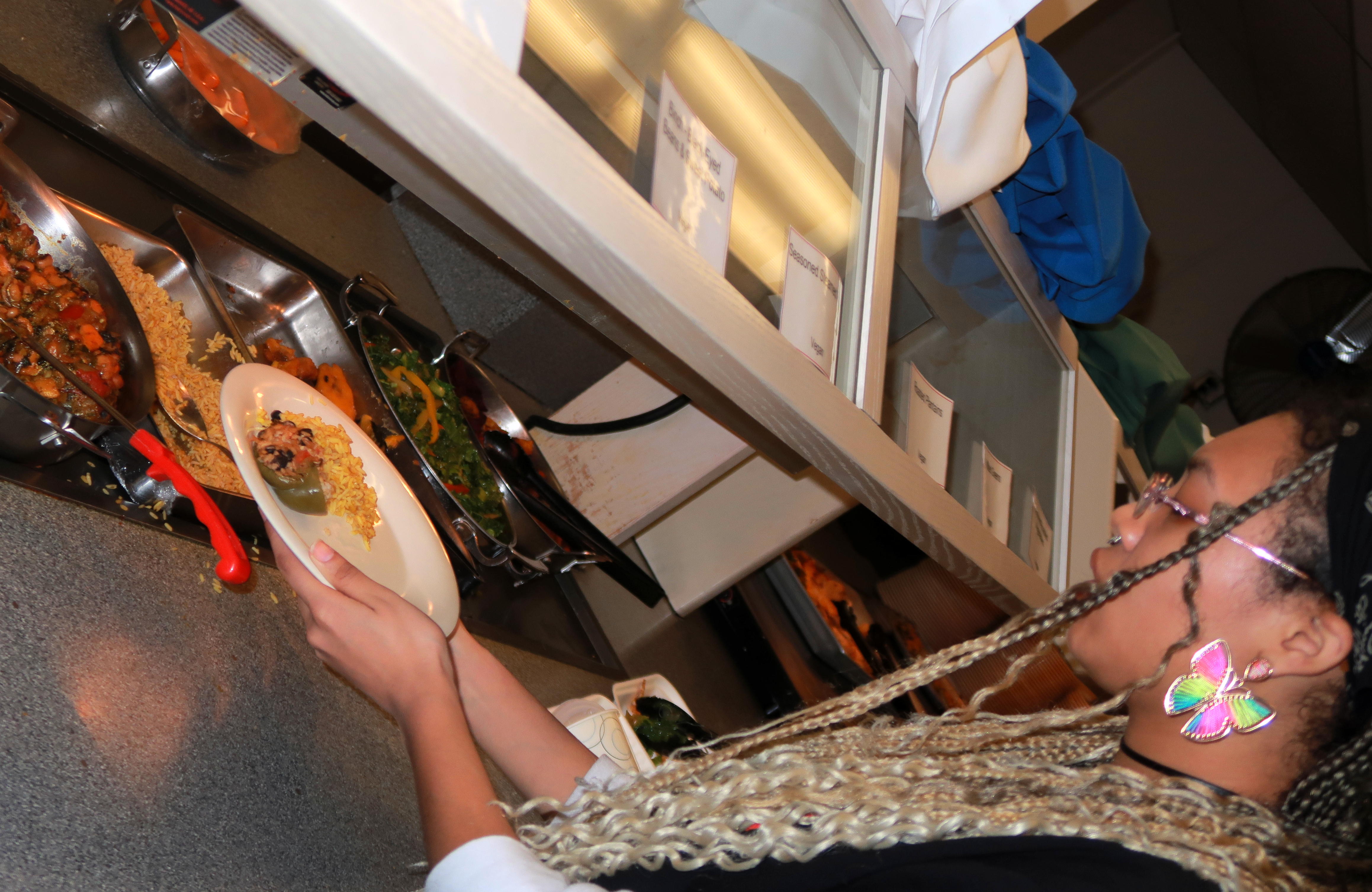 A person serves herself food at Risley's serving line