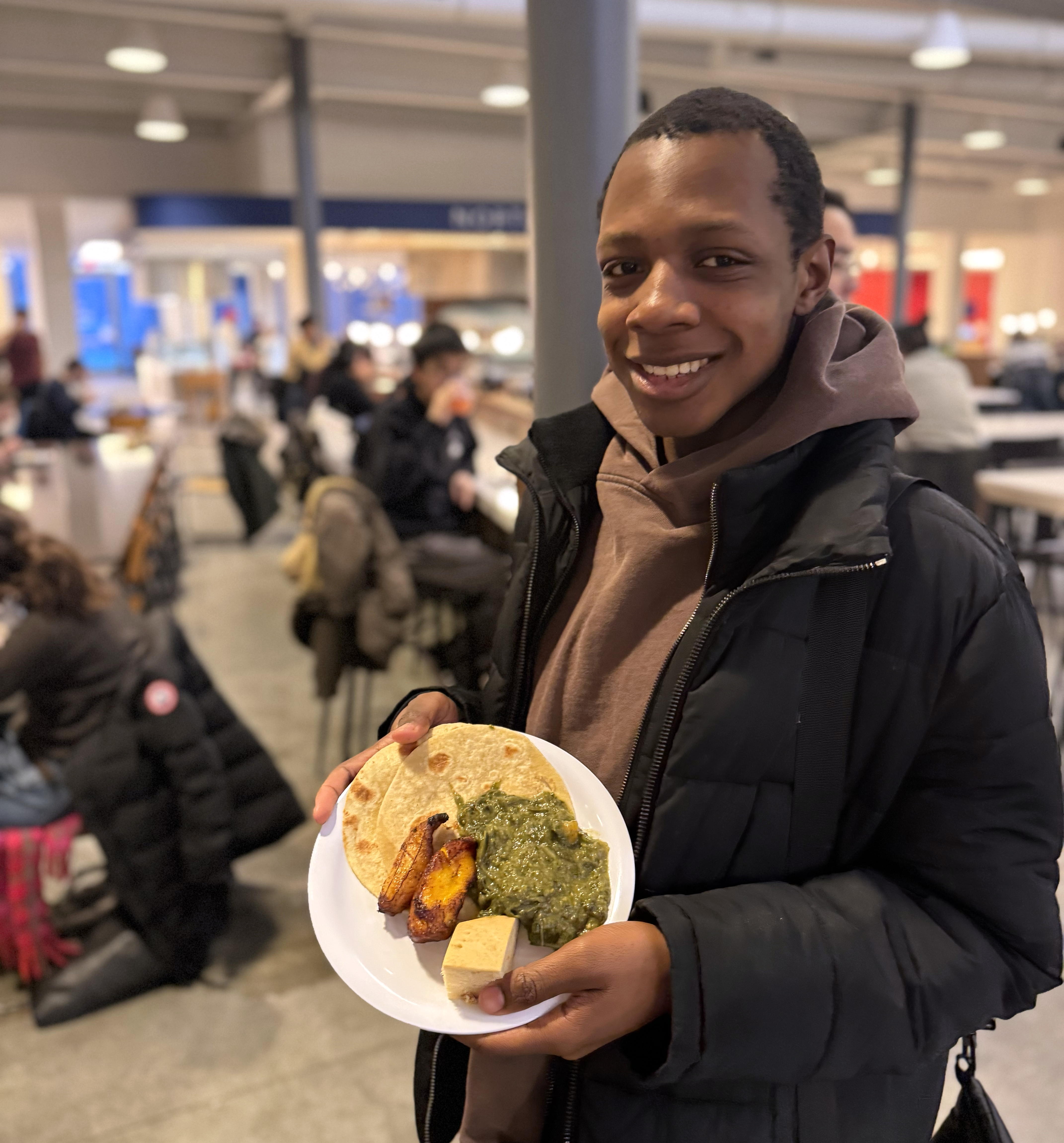 A person smiles holding up a plate of food