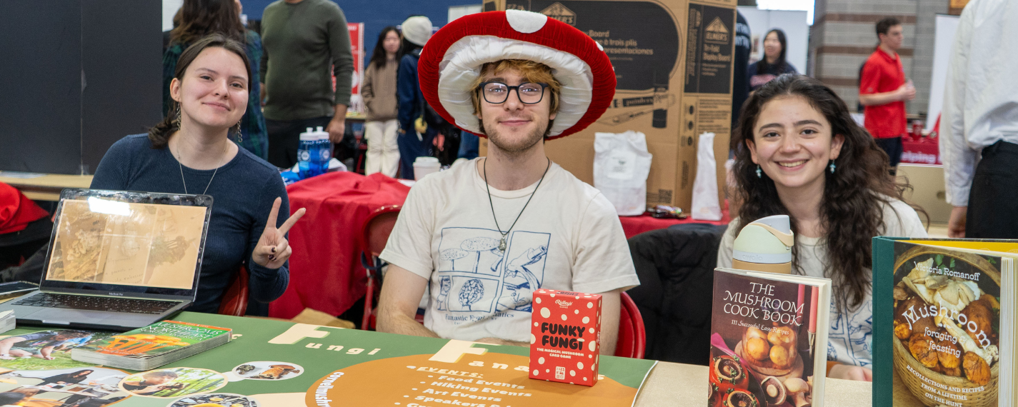 Students sitting and smiling at their clubfest table