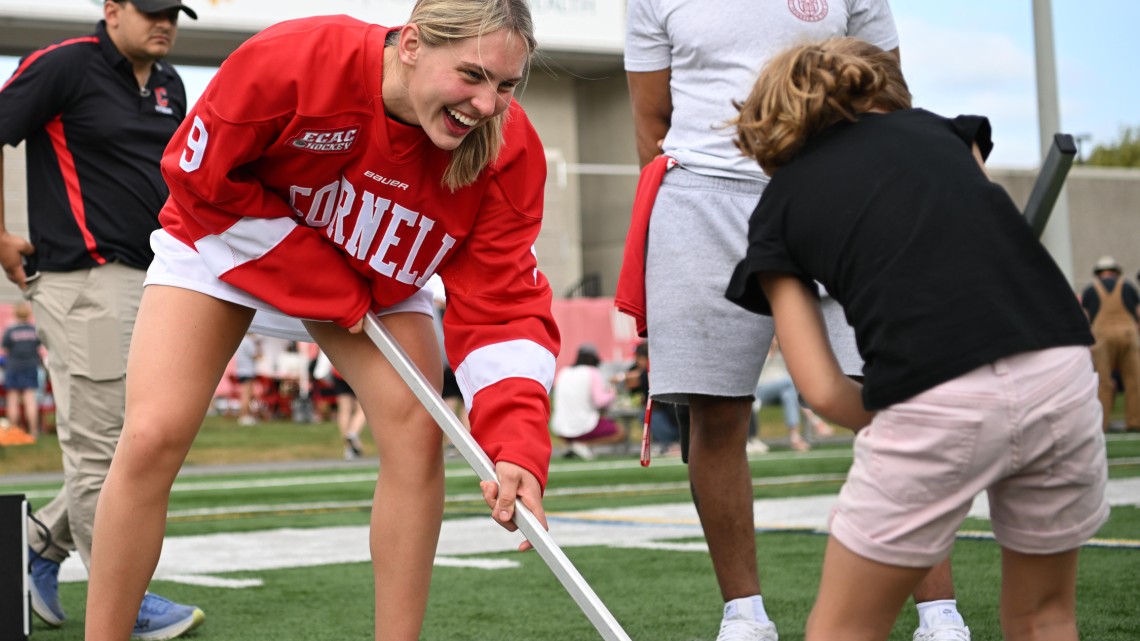 Cornell women’s hockey player Lindzi Avar plays box hockey with a young girl at Cornell Community Field Day.