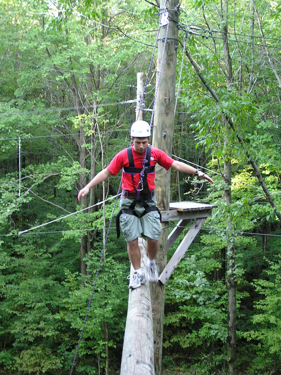 Person walking on the catwalk high ropes course element, 30 feet off the ground.