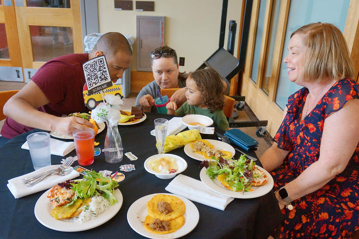 Three adults and a young child around a table with plates of food