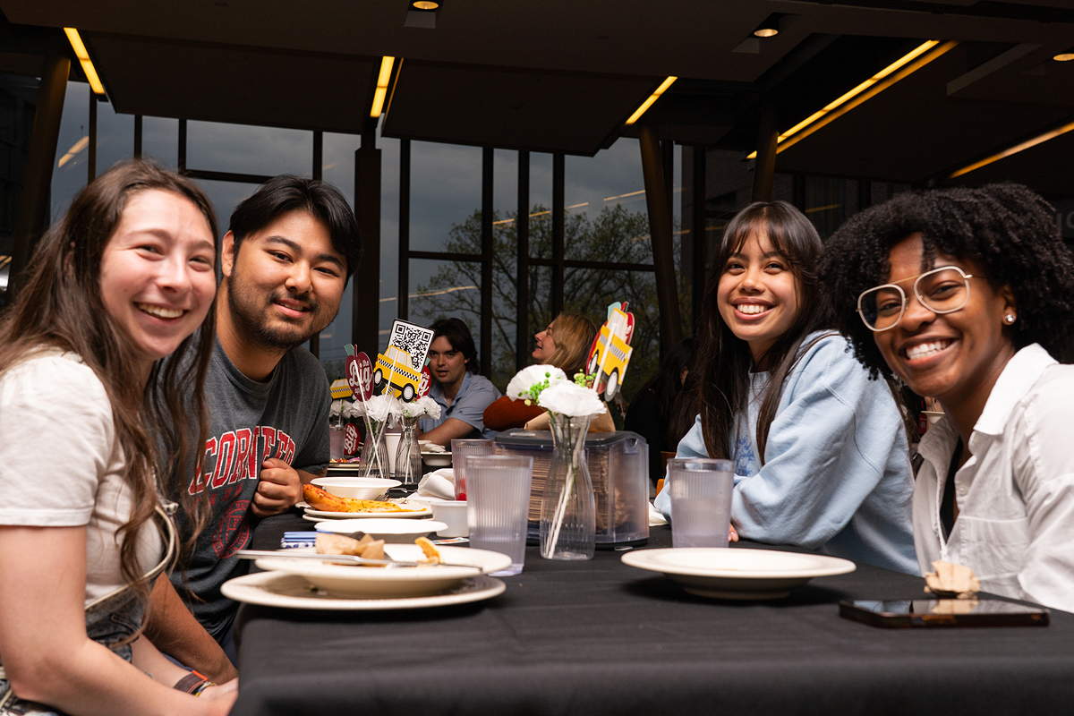 Four people sitting around a dining table, smiling towards us