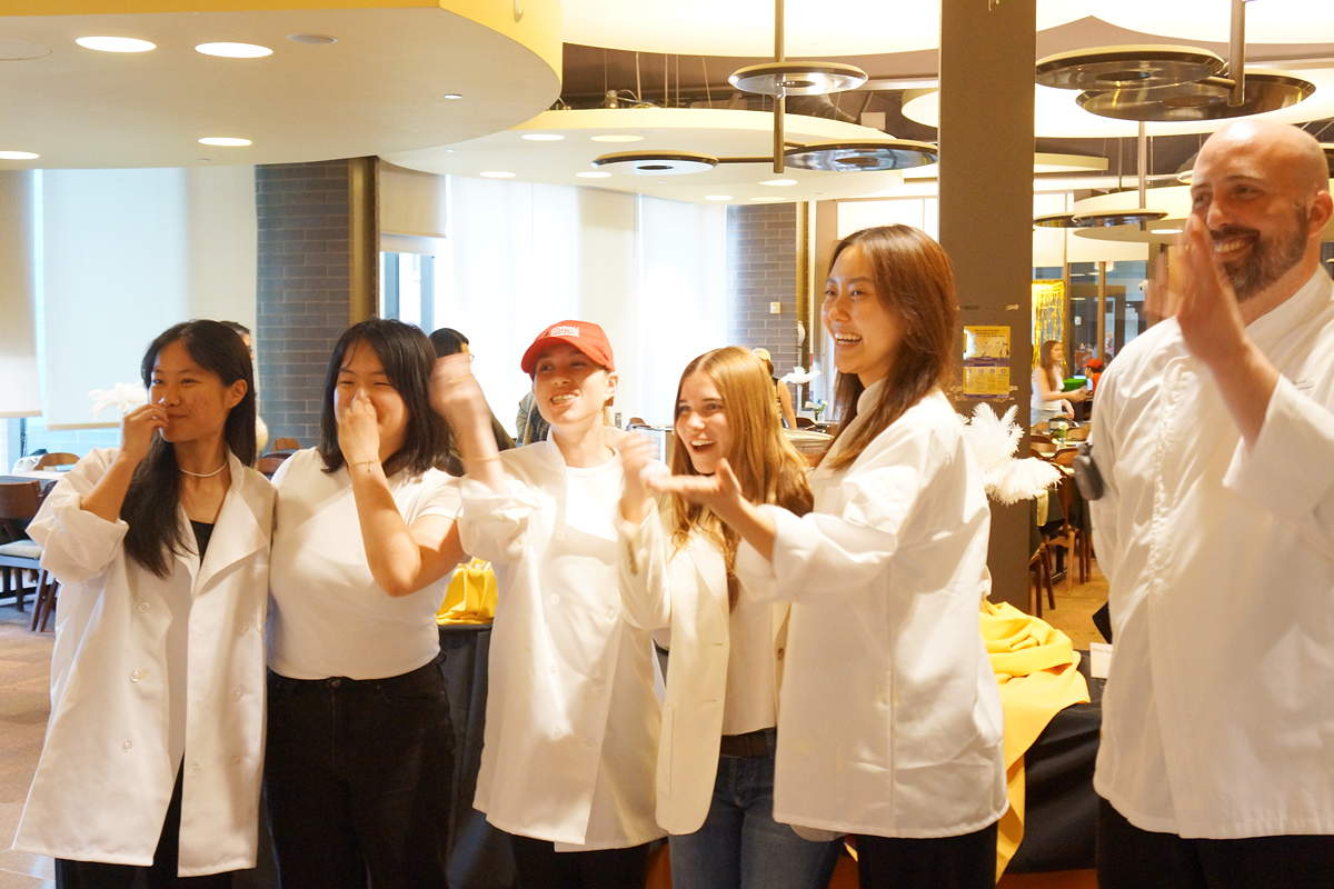 A row of people in chef coats clapping
