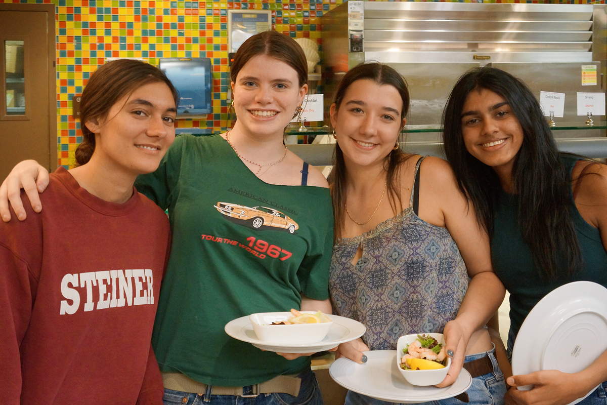Four students smiling and holding plates with food