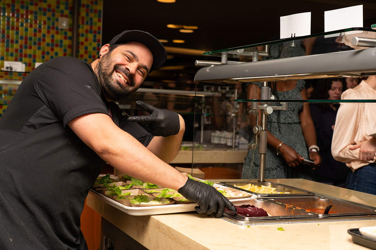 A smiling staff member on the food serving line