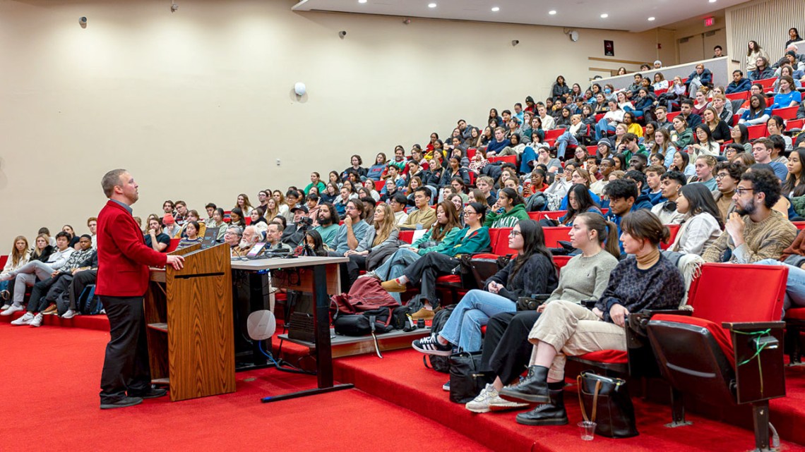 Corey Ryan Earle ’07, the university’s longtime unofficial historian, speaks to a full house in his “Last Lecture” Dec. 4 in Uris Hall Auditorium.