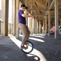 Unicyclist balancing under stadium near columns