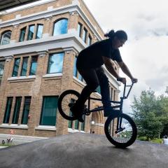 silhouette of bmx biker doing an endo near a big brick building