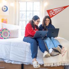 Two residents of Latino Living Center sitting on a bed