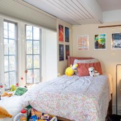 One side of a double room in Latino Living Center with a bed, desk, chair, and window. 