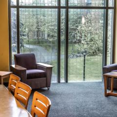 Lounge space in Court-Kay-Bauer Hall with yellow walls, a chair, a couch, a table, and a window
