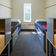 Double room with two twin beds, desks, chairs, lamps, dressers, and a window.