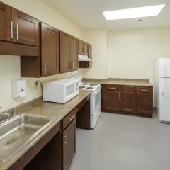A communal kitchen with a sink, fridge, microwave, stove, oven, countertops, and cabinets.