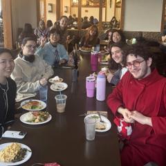 Several people around a dining table smile toward us