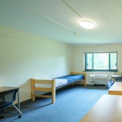 Double room with two twin beds, desks, chairs, lamps, dressers, and a window.