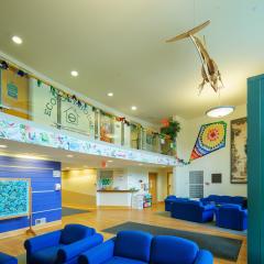 The main lobby and lounge in Ecology House with chairs, tables, a balcony, and bright artwork on the walls.