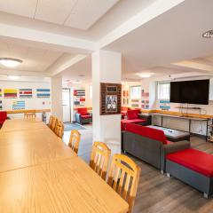 A large lounge in Latino Living Center with tables, chairs, couches, and a tv.