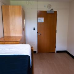 Single room with a twin bed, dresser, and door.