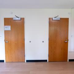 A bedroom with two dressers and two doors.