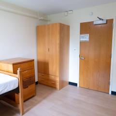 A bedroom with a twin bed, dressers, and a door