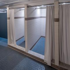 Bathroom with three showers and three stalls.