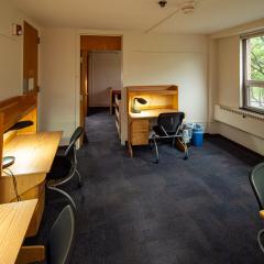 Shared room with four desks and chairs that connects to two double bedrooms