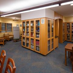 library with wooden tables and chairs as well as bookcases with books
