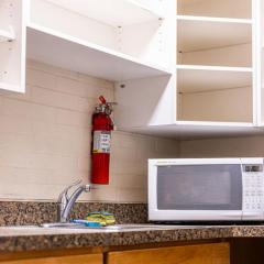 White shelving, a microwave, a fire extinguisher, and a sink in High Rise 5's kitchen