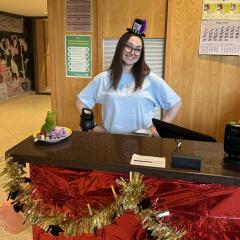 A person with a jaunty hat stands at the dining room front desk